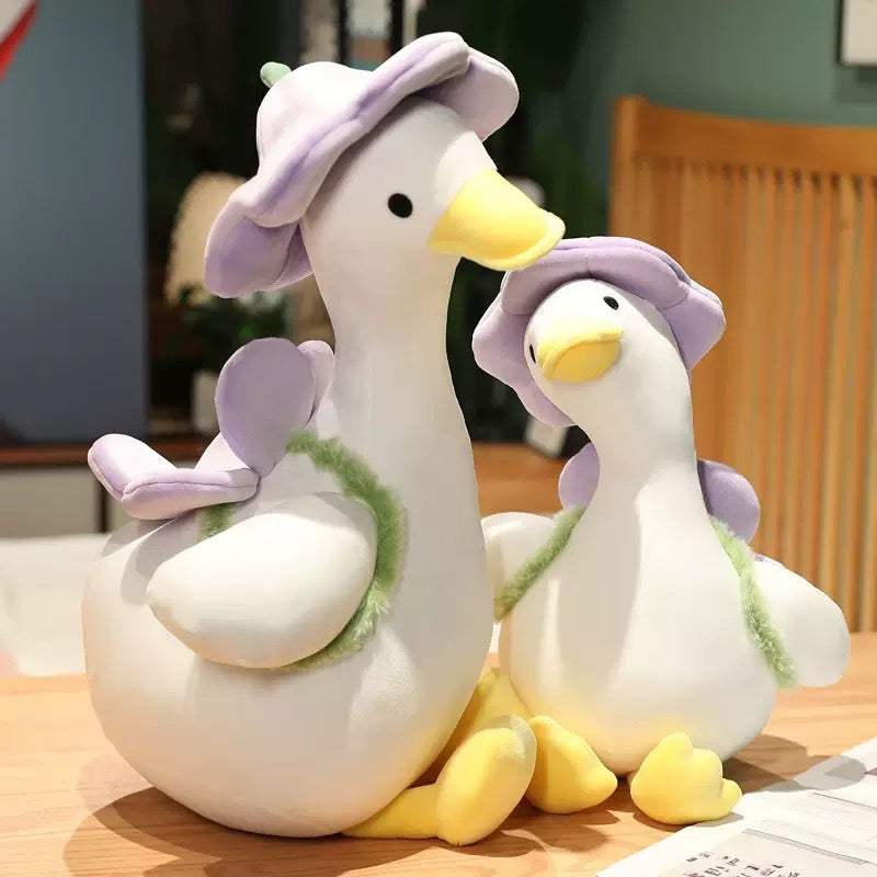 The duck plush toy, with a hat and a small flower on its back, feels as comfortable as a cloud, exuding a youthful spring-like atmosphere. It is a gift, a companion, and adds fun.