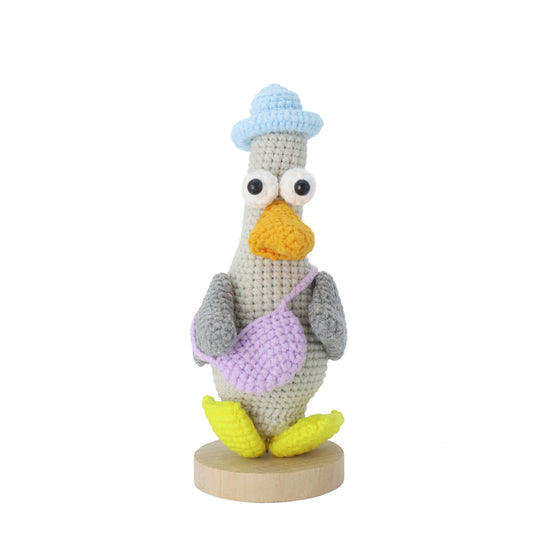 Hand-crocheted Mr. Duck, adorned with a blue hat and a purple messenger bag, features a pair of prominent big eyes, making it adorably cute