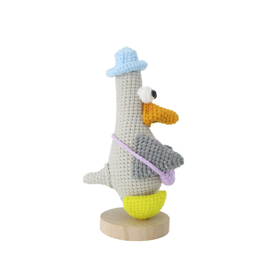 Hand-crocheted Mr. Duck, adorned with a blue hat and a purple messenger bag, features a pair of prominent big eyes, making it adorably cute