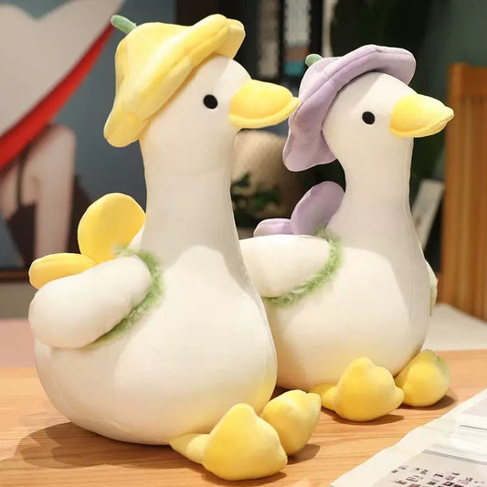 The duck plush toy, with a hat and a small flower on its back, feels as comfortable as a cloud, exuding a youthful spring-like atmosphere. It is a gift, a companion, and adds fun.